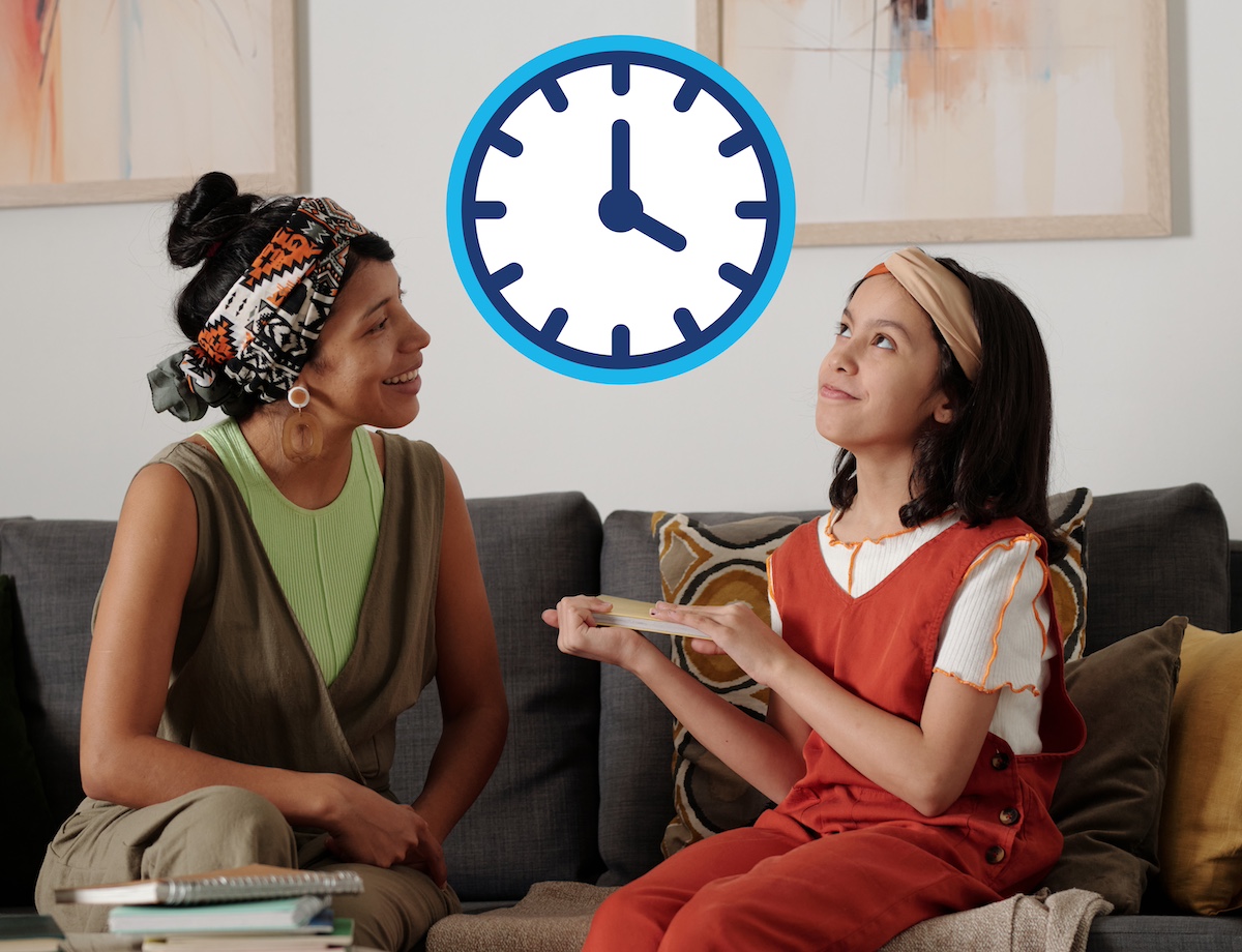 A woman and a girl are having a chat on the sofa. The girl is thinking, the woman is listening and smiling. The symbol of a clock between them indicates that they are not in a rush.